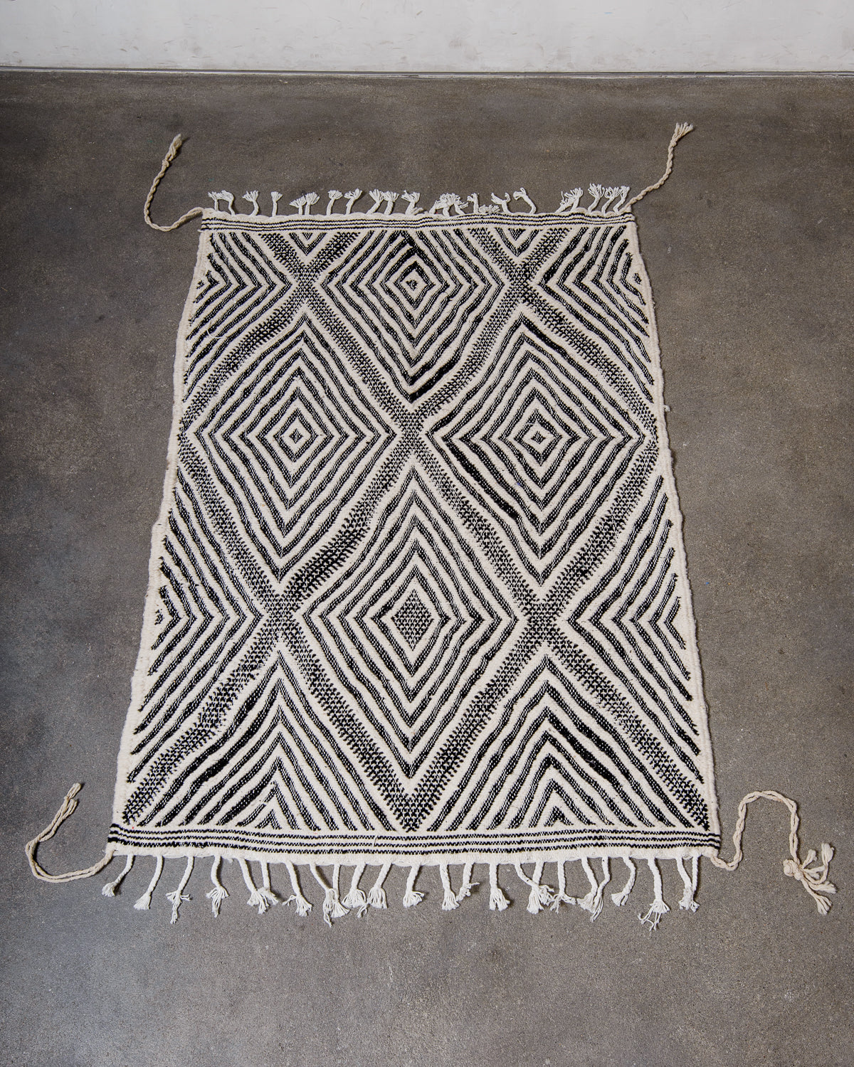 Small Kelim Rug in black and white laying on concrete studio floor.